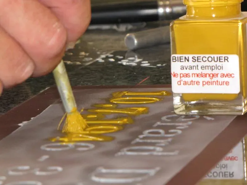 Application de peinture dorée au pinceau sur des lettres gravées