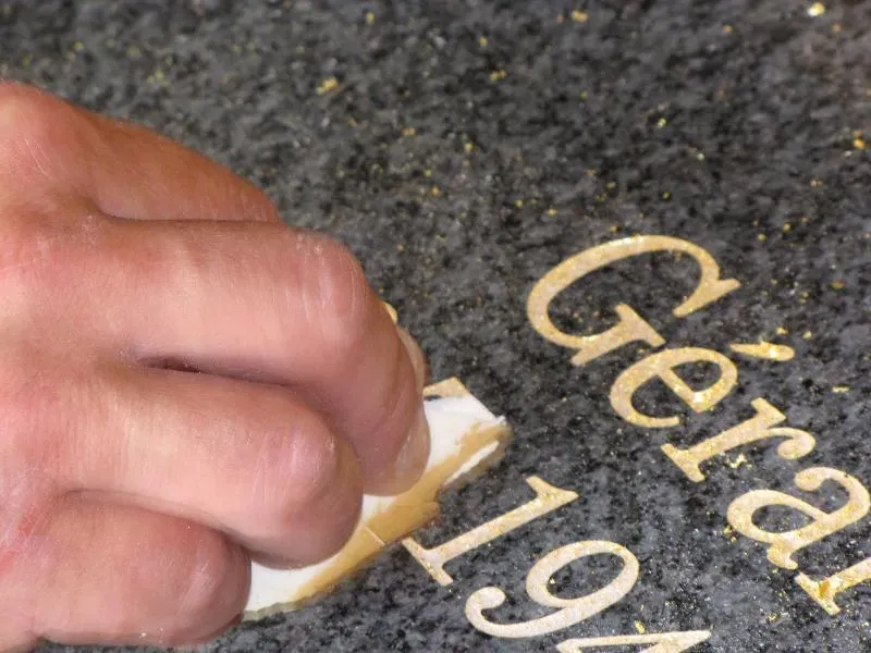 Finition et grattage minutieux des dorures sur la pierre gravée