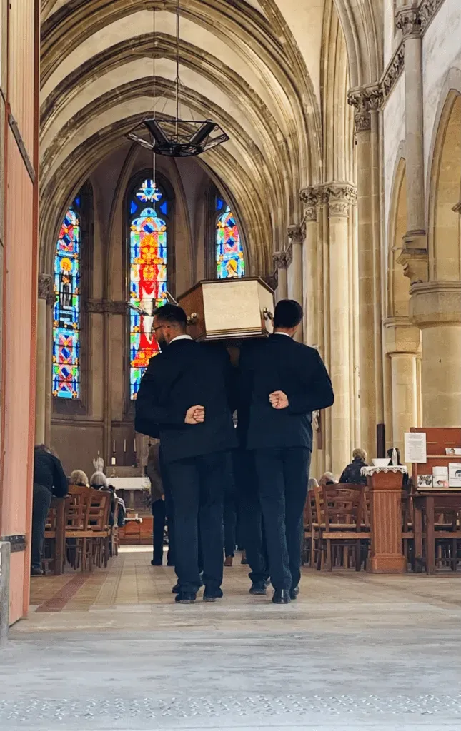 Porteurs en costume portant un cercueil dans une église